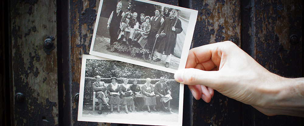 A hand holding 2 old photographs