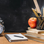 Typical teacher's desk with clock pencils and chalkboard